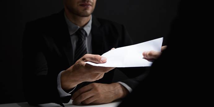 Man handing over a document to another person