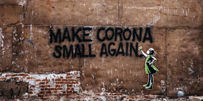 Brick wall spray painted with a little girl and slogan saying make corona small again
