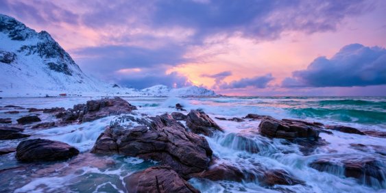 waves crashing over rocks during sunset