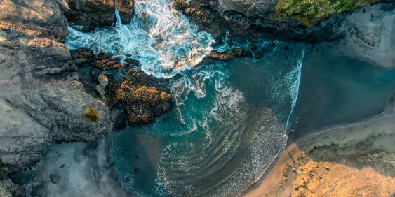 Aerial view of waves crashing against rocks on the shore