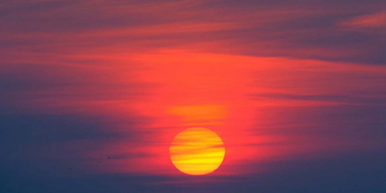 Close up of a sun during sunset through dark clouds