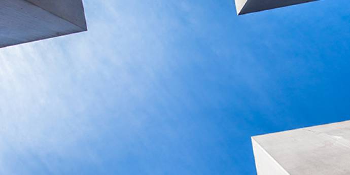 looking up between buildings to a blue sky