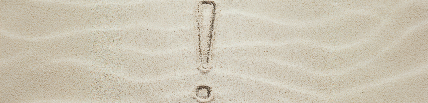 A exclamation mark drawn in smooth, light brown sand. 