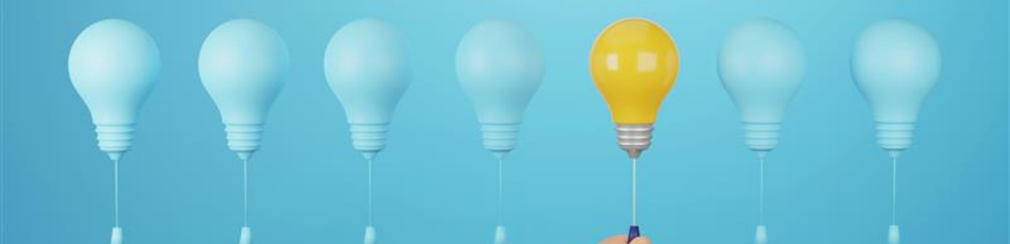 A hand holds a glowing light bulb in front of a row of unlit bulbs, symbolizing innovation and ideas.