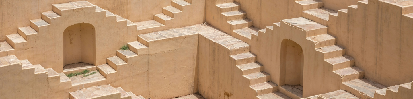 Stepped water well with symmetrical pattern of stairs and arched doorways on sandy-colored walls