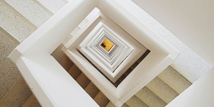 A white staircase illuminated by a warm yellow light positioned in the center, creating a welcoming atmosphere.