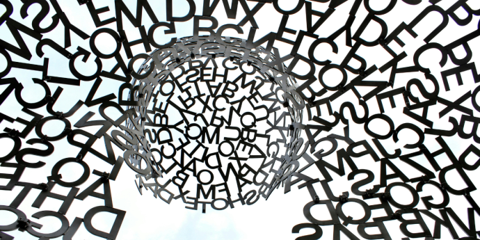 An oversized metal sculpture featuring an intricate design made entirely of letters, highlighting creativity and language.