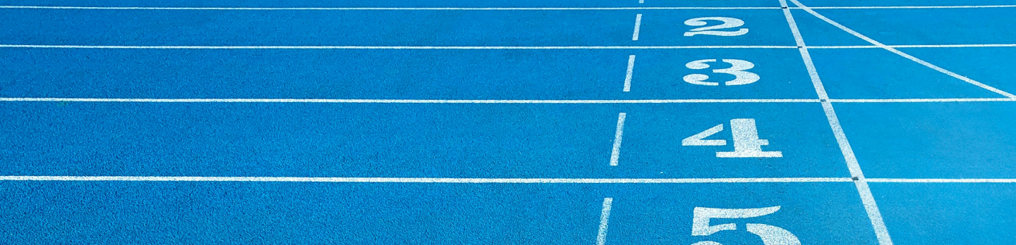 Blue running track with white lane numbers 1–6, lane lines, and a yellow marking near lane 6, evoking speed, competition, and athletic focus.