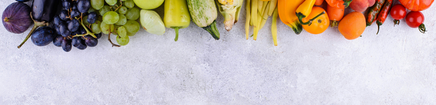 A colorful assortment of fruits and vegetables arranged in a line, showcasing a rainbow spectrum. 