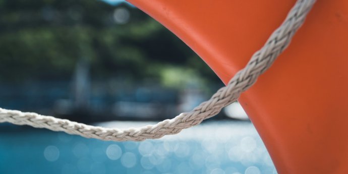 An orange life preserver is securely tied to the side of a boat, ready for use in case of an emergency.