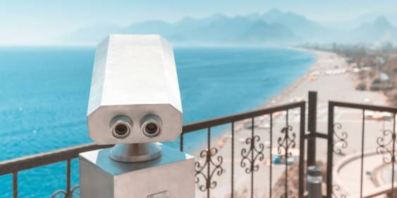 A pair of binoculars on a railing, overlooking a scenic view of the sea.