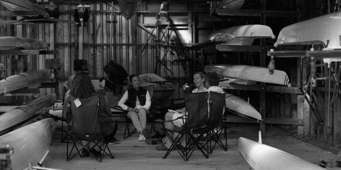 A group of people seated in chairs inside a garage, engaged in conversation and sharing ideas