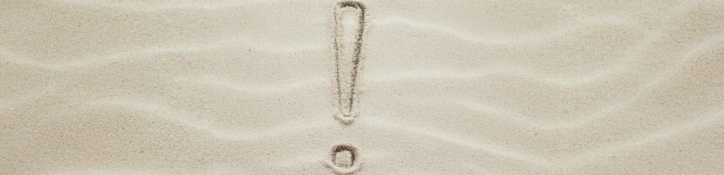 A exclamation mark drawn in smooth, light brown sand. 