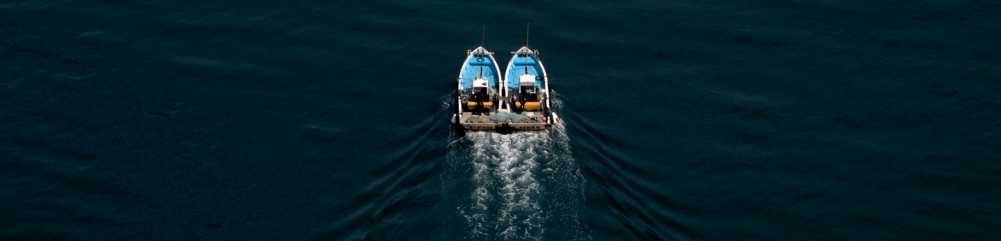 Two small boats floating gently on calm water under a clear blue sky.