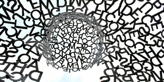 An oversized metal sculpture featuring an intricate design made entirely of letters, highlighting creativity and language.