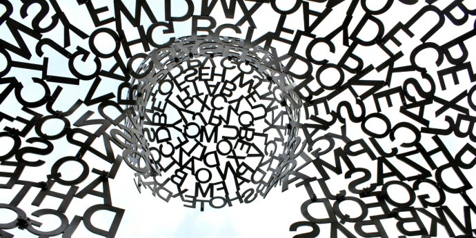 An oversized metal sculpture featuring an intricate design made entirely of letters, highlighting creativity and language.