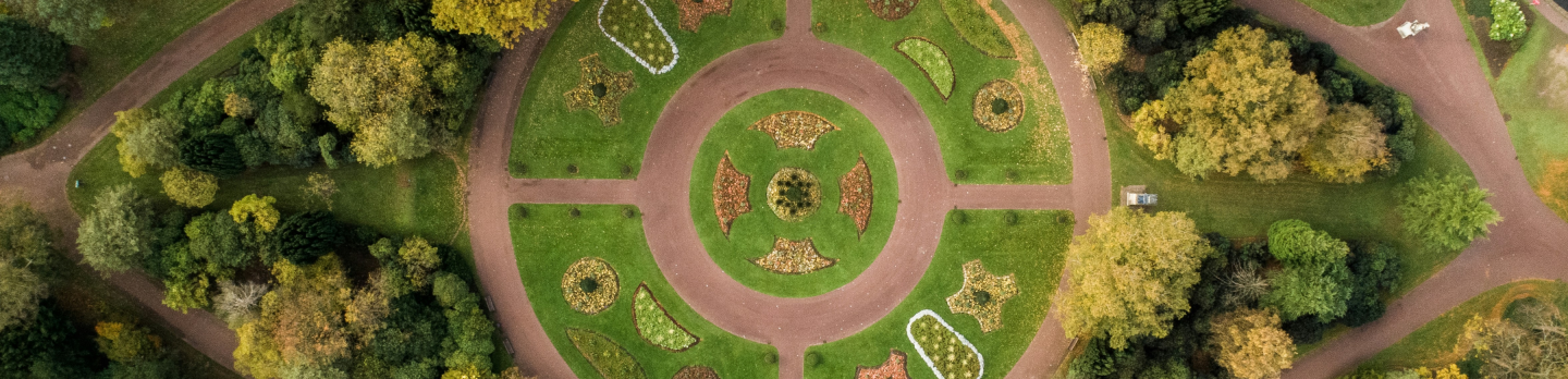 Aerial view of a circular garden with intricate paths and vibrant green grass.