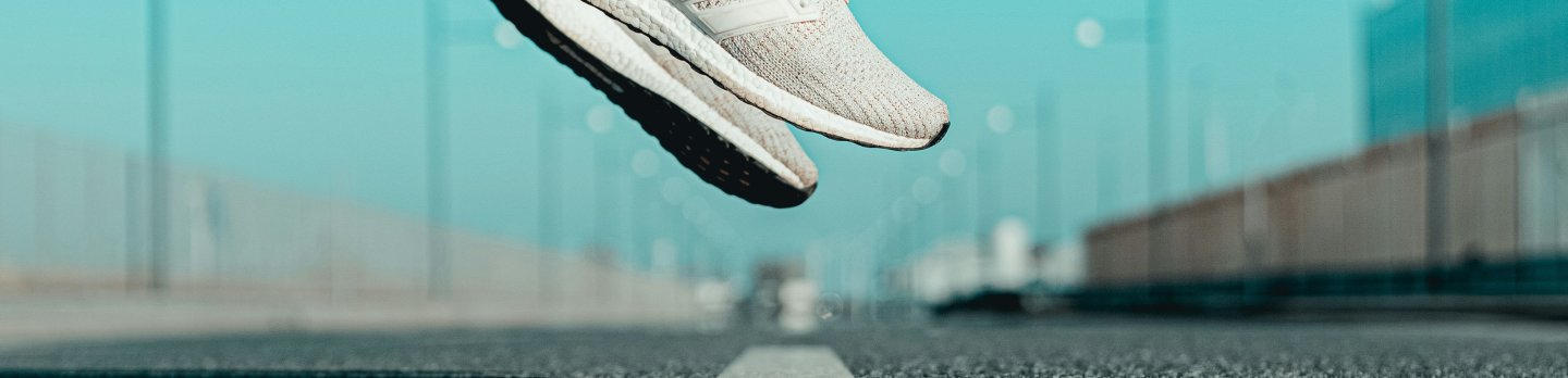 A white sneaker is airborne, highlighting its modern style and dynamic movement.