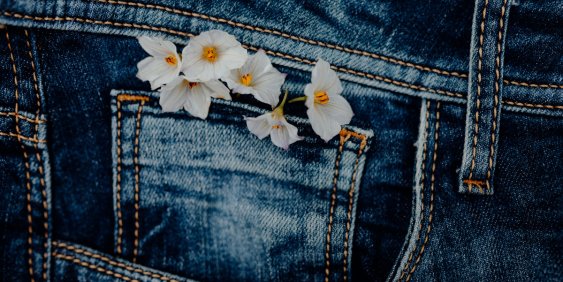 A pair of denim jeans with a pocket adorned by bright flowers, showcasing a unique blend of fashion and nature.