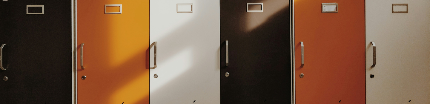 Row of colorful lockers with metal handles: black, orange, white, dark brown, and red. 