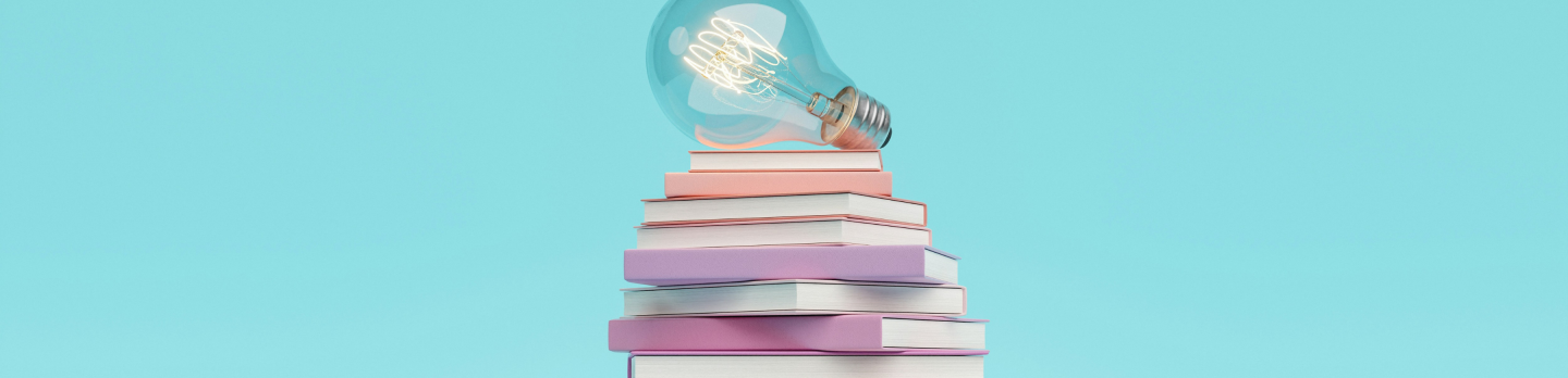 A light bulb sits atop a stack of books, representing inspiration and learning.