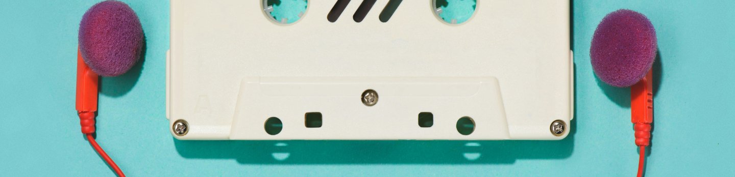 A white cassette tape lies flat on a blue background, flanked by two purple foam-covered earbuds with red cords, conveying a retro, nostalgic vibe.