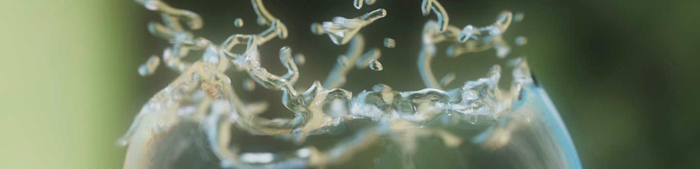 A translucent bubble partially bursting with droplets of water radiating outward. 
