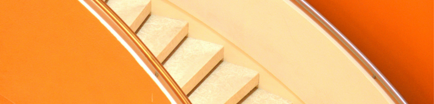 A stylish spiral staircase featuring white and orange colors, elegantly twisting upward in a contemporary setting.