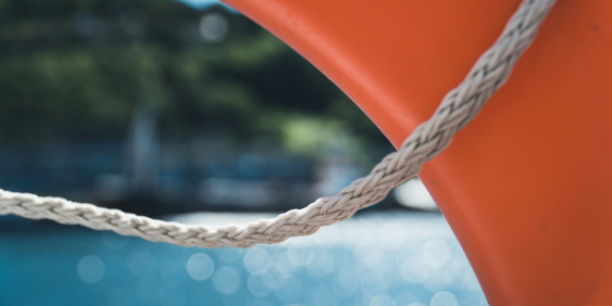 An orange life preserver is securely tied to the side of a boat, ready for use in case of an emergency.