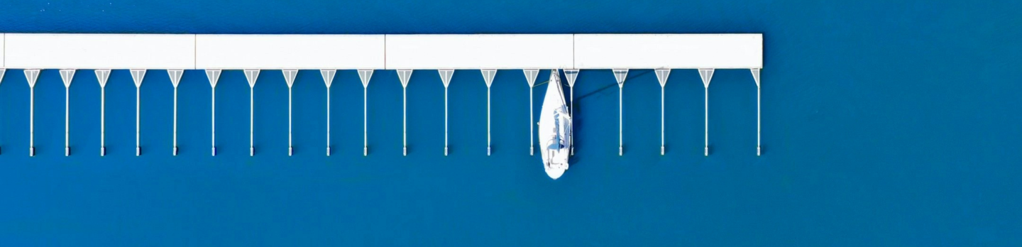 A white horizontal rack with evenly spaced thin hanging strands and a small central dangling ornament against a deep blue background, serene and minimal.