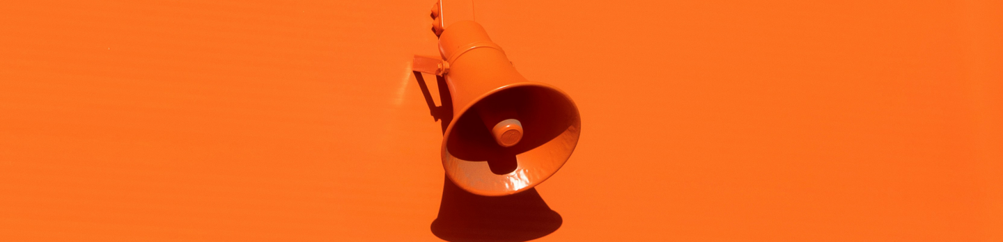 Orange megaphone centered on a vivid orange background, casting a dark shadow; minimalist composition with a bold, energetic tone.