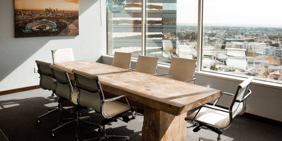 Office room displaying a board table positioned next to glass windows looking out to the city views
