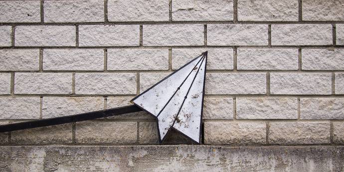 Paper plane against a brick wall