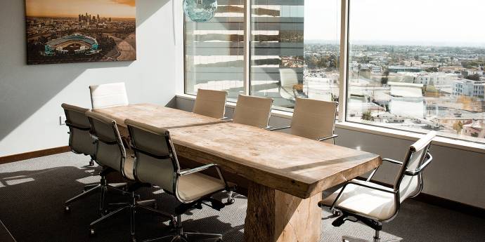 Office room displaying a board table positioned next to glass windows looking out to the city views
