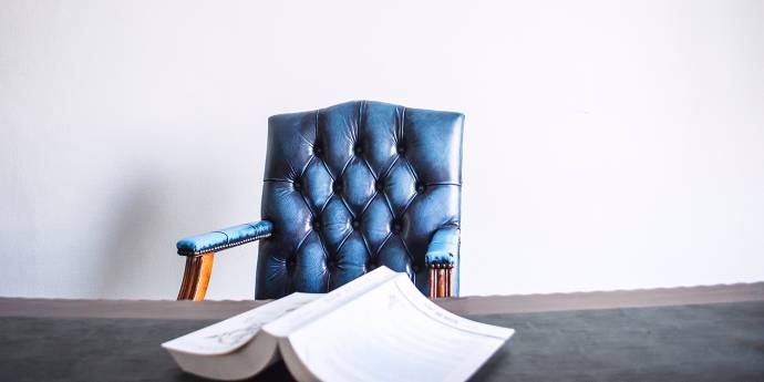 Blue chair at a table with a book on the table. 