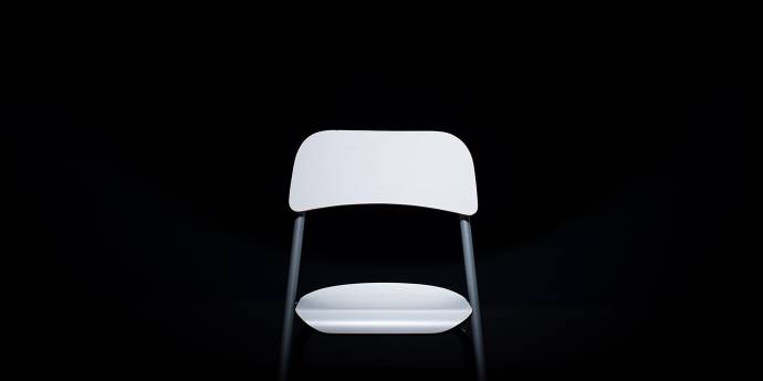 white plastic chair against dark black background