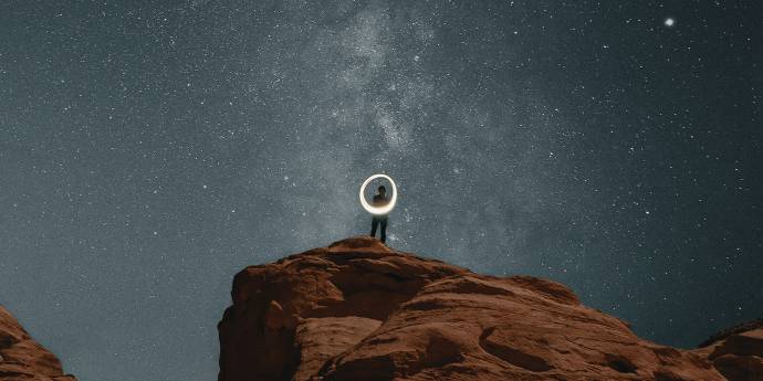 Person standing on a rock at night with starry sky