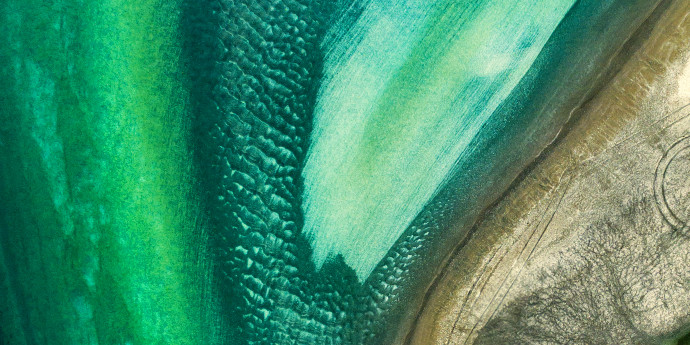 looking down on beach and green sea