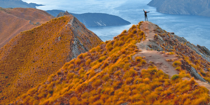 Person standing on mountain top with arms raised