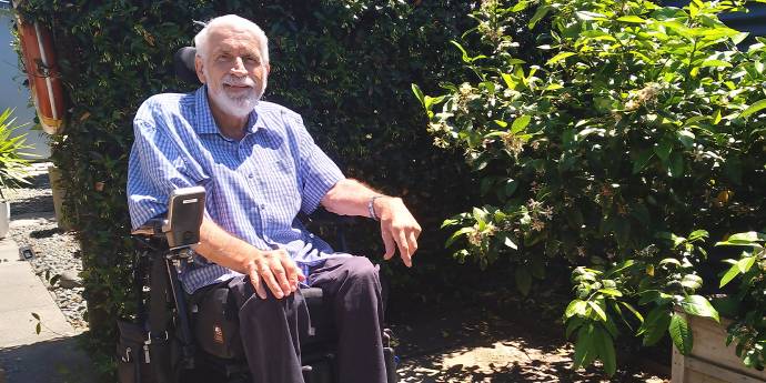 Paul Curry in a wheelchair sitting in a garden on a sunny day
