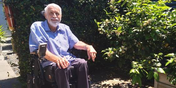 Paul Curry in a wheelchair sitting in a garden on a sunny day