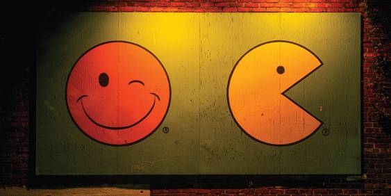 Painting of pacman and a smiley face on a brick wall