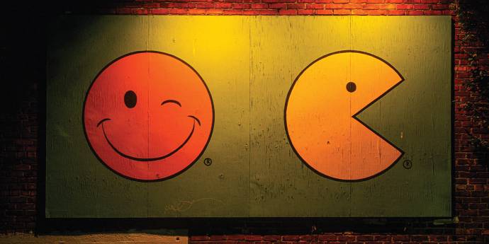Painting of pacman and a smiley face on a brick wall