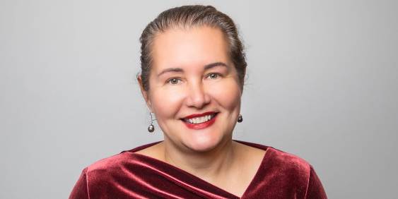 Mele Wendt smiling, wearing a red top. 