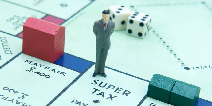 A male figurine standing on a monopoly board surrounded with dice and small houses 
