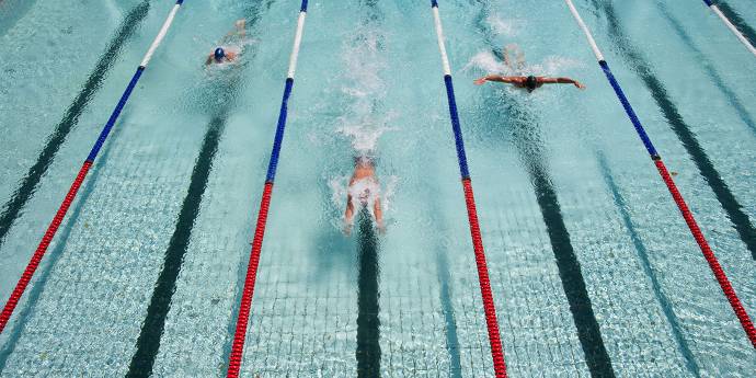 Three swimmers, swimming in a multiple lane pool 