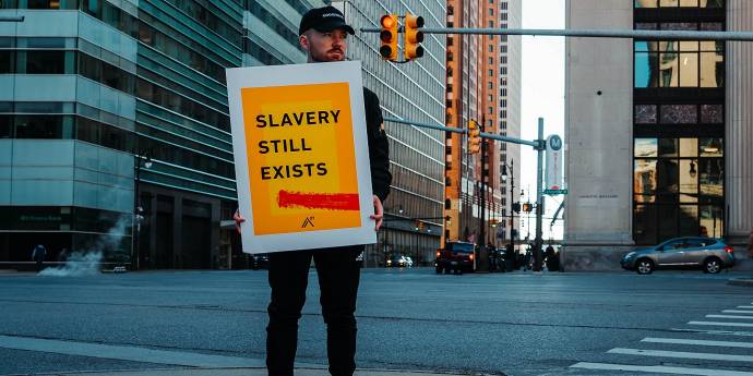 person in street holding a sign that says slavery still exists