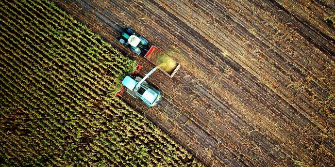 Birds eye view of two tractors and farmers cropping in a field. 