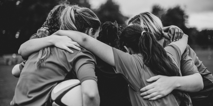 team of female rugby players in a huddle