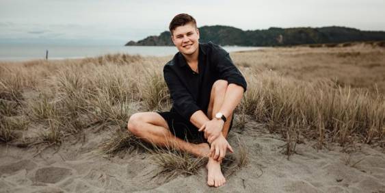 Te Aorangi Murphy-Fell sitting on a beach